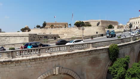 24-July-2021,-Aerial-drone-view-of-Central-Bank-of-Malta-in-Valletta,-from-Herbert-Ganado-Garden-in-Floriana-with-tourists-in-foreground