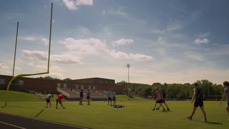 Runners-on-track-and-field-walk-to-coach-for-team-meeting-on-a-hot-summer-day