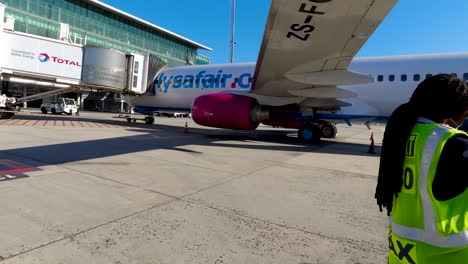 FlySafiar-Jet-standing-on-the-tarmac-as-passenger-records-after-arrival-in-Cape-Town