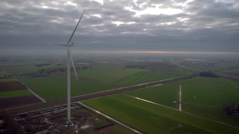 Wind-turbine-with-overcast-weather-in-the-nNetherlands,-along-with-train-tracks-in-the-background