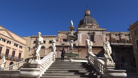 Young-female-tourist-taking-a-selfie-in-front-of-Fontana-Pretoria-in-centre-of-Palermo,-Sicily,-Italy