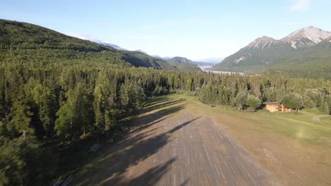 Drone-or-UAV-aerial-dolly-shot-of-a-takeoff-from-a-private-grass-runway-in-a-remote-portion-of-the-Talkeetna-Range