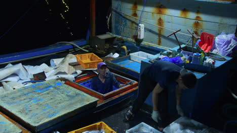 Fisherman-unloading-fresh-caught-fish-tray-from-boat-for-trading-in-largest-fishing-market-at-Tho-Quang-Port,-Vietnam