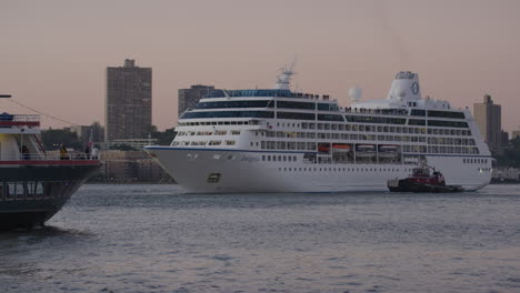 Vorschiff-Eines-Kreuzfahrtschiffes-Mit-Schlepper-Auf-Dem-East-River,-Während-Bei-Sonnenuntergang-Ein-Weiteres-Fährschiff-Vorbeifährt