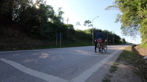 Two-cyclist-walking-on-a-highway-in-Cao-Bang-province,-Vietnam-and-dragging-their-cycles-loaded-with-luggage