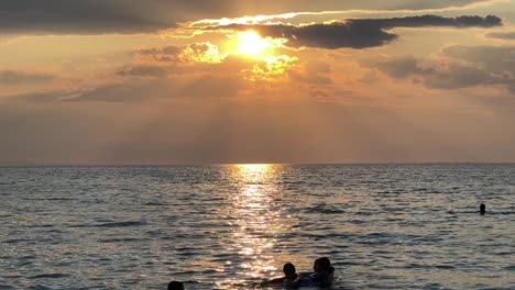 Silueta-De-Un-Hombre-Vendiendo-Donas-Dulces-Caminando-Por-La-Playa-Durante-El-Atardecer