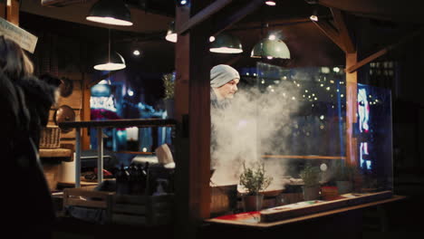 Chef-Limpiando-La-Sartén-Humeante-Mientras-Prepara-Comida-Tradicional-Estonia-En-El-Mercado-Navideño---Tallin,-Estonia