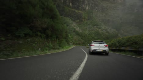 Car-coming-around-corner-on-mountain-pass-road-during-cloudy-day,-tracking-shot