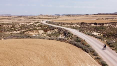 Wüste-Bardenas-Reales,-Navarra,-Argueddas,-Spanien---Luftaufnahme-Eines-Touristen-Per-Drohne-Beim-Mountainbiken-Durch-Die-Atemberaubende-Landschaft