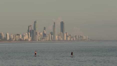 28-De-Enero-De-2023---Gente-Surfeando-En-Burleigh-Heads-Al-Amanecer-Con-El-Paraíso-De-Los-Surfistas-Al-Fondo-En-La-Costa-Dorada,-Queensland,-Australia