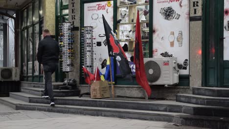 Dueño-De-Tienda-Arreglando-La-Bandera-Albanesa-En-Mitrovica,-Kosovo