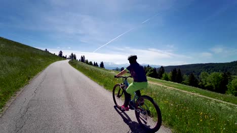 Professional-Mountain-Biker-on-sport-bicycle-driving-uphill-on-asphalt-road-in-italian-mountains-during-summer