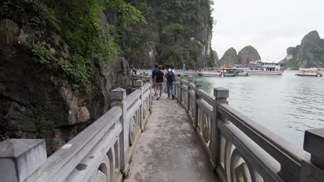 Walking-on-pathway-along-Ha-Long-Bay-next-to-the-sea-with-boats