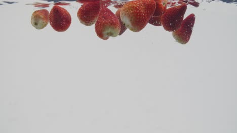 Whole-strawberries-splashing-in-water