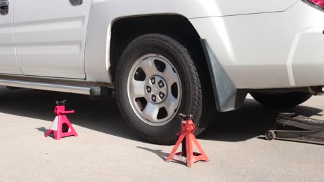 Shade-Tree-Mechanic-Jacking-Up-Back-of-a-White-Truck-with-Floor-Jack