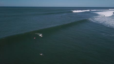 Surfers-attempt-to-ride-large-waves-in-the-shores-of-the-Cocal-Beach-in-La-Libertad,-El-Salvador