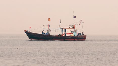 Ein-Kleines-Fischerboot,-Das-Mitten-Im-Meer-Segelt,-Mit-Einem-Fischer,-Der-Sich-Bei-Sonnenuntergang-Mit-Kleinen,-Ruhigen-Wellen-Auf-Das-Anlegen-Vorbereitet-Und-Bei-Nebligem-Wetter-Nach-Hause-Zurückkehrt.-Videohintergrund-In-Mov-In-Full-HD