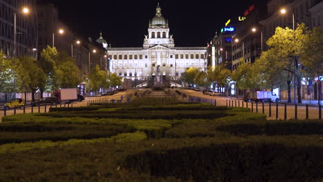 A-view-of-the-National-museum-in-Prague,-Czechia-on-the-empty-Wenceslas-square-with-in-the-historical-centre,-lit-by-street-lamps-during-a-Covid-19-lockdown,-pedestal-shot-over-neatly-trimmed-hedges