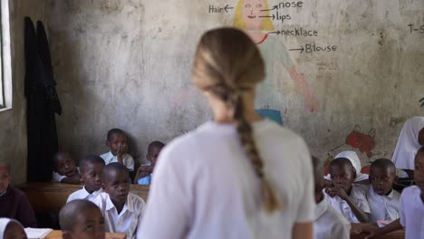 Chica-Rubia-Caucásica-Blanca-Enseñando-Como-Voluntaria-En-Una-Escuela-Africana-Con-Niños-Pequeños