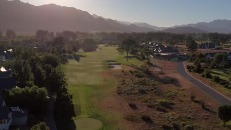 Vista-Aérea-Del-Campo-De-Golf-Al-Atardecer-Con-Un-Rico-Césped-Verde,-Putting-Green,-Búnker-De-Arena-Y-Obstáculos-De-Agua-En-Pearl-Valley-Golf-Estate-And-Spa,-Cabo-Occidental,-Sudáfrica