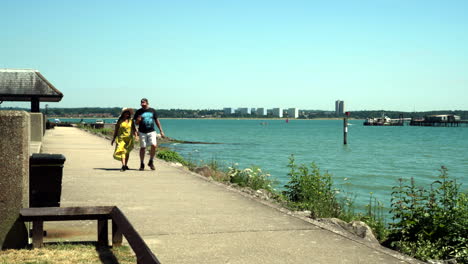 Una-Pareja-De-Turistas-Indios-Caminando-Y-Disfrutando-Del-Ambiente-En-Hythe-Marina-En-Hythe,-Inglaterra,-Reino-Unido.