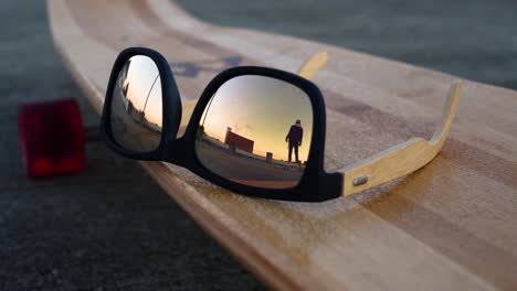 Man-skates-by-in-reflection-of-glasses-on-a-skateboard-in-slow-motion