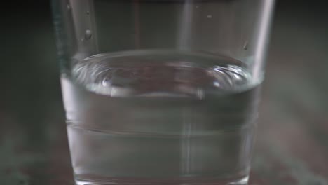 Verter-Agua-En-Un-Vaso-De-Cerca-Sobre-El-Fondo-Oscuro.