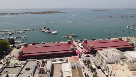 Fish-and-meat-market-in-historic-brick-and-metal-building-in-Olhão,-aerial-orbit