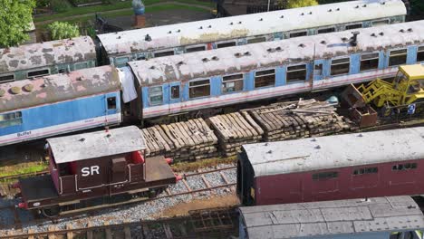 Aerial-dolly-view-Ironstone-railway-trust-disused-locomotive-freight-carriages-and-train-trucks