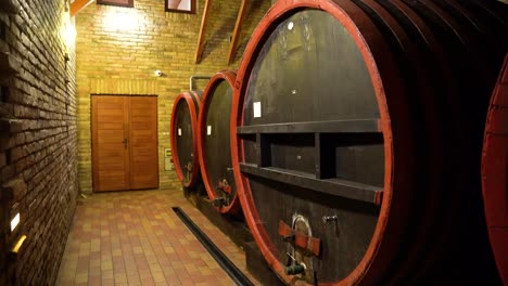 A-wine-cellar-featuring-large,-dark-brown-wooden-barrels-with-red-painted-frames