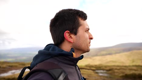 Close-up-of-a-man-zipping-his-jacket-in-Brecon-Beacons-National-Park-on-a-cold,-windy-day