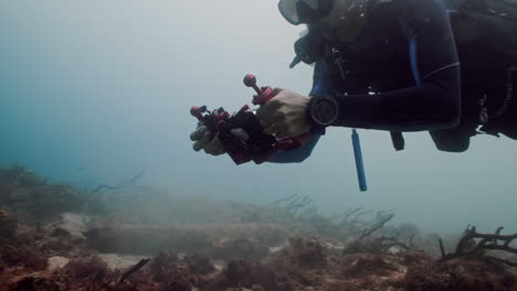 Underwater-shot-of-a-diver-taking-pictures-of-corals-and-adjusting-the-camera-settings-while-swimming-in-a-Caribbean-reef