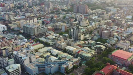 Aerial-tilt-up-shot,-drone-flyover-capturing-the-sunset-downtown-cityscape-of-Douliu-city,-Yunlin-county,-the-countryside-of-Taiwan