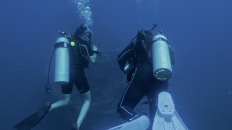 Two-marine-biologist-diving-around-ship-wreckage