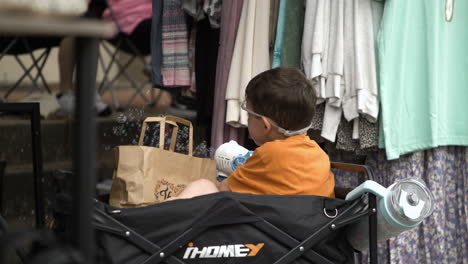 Adorable-Toddler-In-Baby-Stroller-Playing-Bubble-Toy-Gun-At-50th-Dogwood-Festival-In-Siloam-Springs,-Arkansas