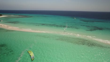 Kite-surfers-enjoy-crystal-clear-turquoise-waters-near-a-white-sandy-beach-on-a-sunny-day