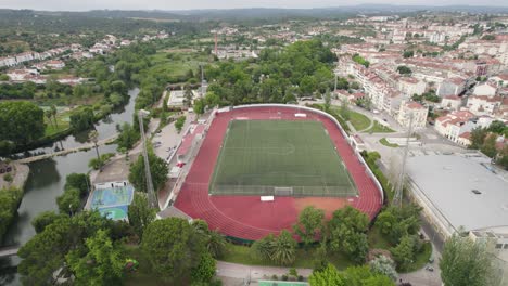 Estadio-De-Fútbol-En-Tomar,-Portugal,-órbita-Aérea-Con-El-Horizonte-De-La-Ciudad,-Día-Nublado