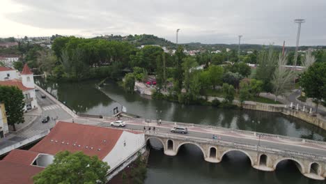 Autos-Fahren-über-Die-Mittelalterliche-Brücke-Und-Den-Fluss-Nabao-In-Tomar,-Portugal,-Luftaufnahme