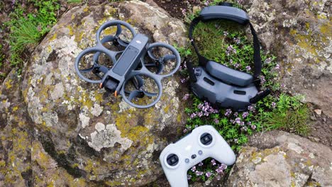 FPV-drone-set-with-goggles-and-remote-control-on-rocky-outdoor-surface