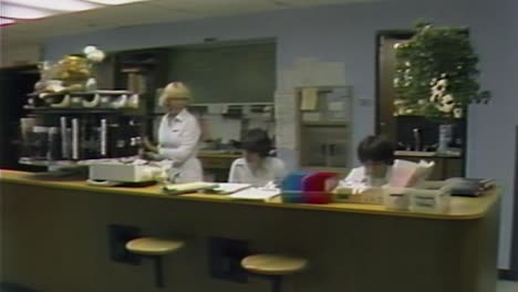 1970S-NURSES-BEHIND-COUNTER-AT-A-HOSPITAL-WORKING