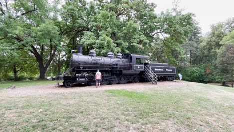 Tourist-looks-at-old-locomotive-in-Avery-Park,-Corvallis-Oregon