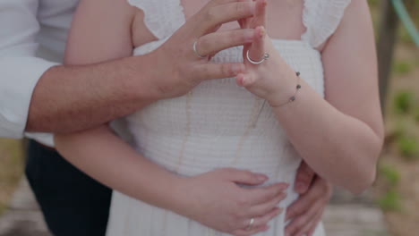 Close-up-of-a-couple-embracing,-showing-their-hands-and-rings,-with-a-soft-focus-on-their-torsos