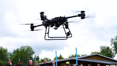 Un-Dron-De-Reparto-Con-Sistema-De-Cable-Retráctil-Despega-En-Un-Evento-Al-Aire-Libre