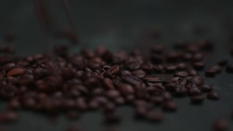 Close-up-of-coffee-beans-falling,-spilling-onto-the-dark-table