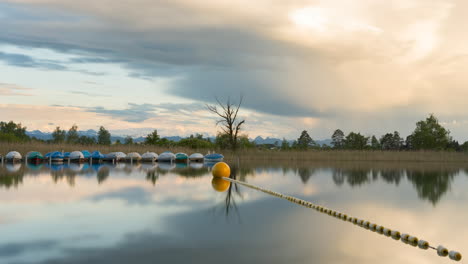 Das-Sanfte-Licht-Des-Sonnenuntergangs-Zur-Goldenen-Stunde-Breitet-Sich-über-Den-Wolken-über-Kleinen-Booten-Am-Seesteg-In-Der-Schweiz-Mit-Ruhigem-Wasser-Aus