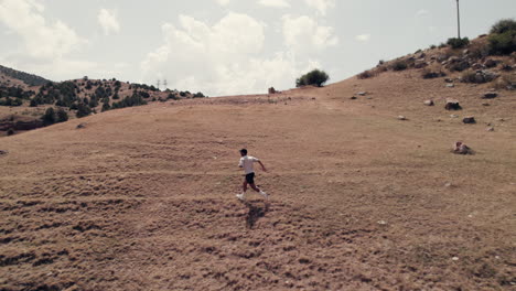 In-aerial-capture-over-Zaamin-Province,-a-male-runner-dashes-across-rugged-terrain