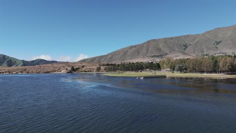 Forward-shot-of-artificial-lake-with-sky-blue-reflection-in-the-town-of-Tafí-del-Valle-in-Tucumán,-Argentina-with-rows-of-hills-on-the-sides