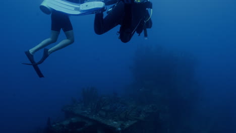 Two-marine-biologist-diving-around-ship-wreckage