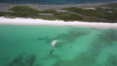 Un-Kitesurfista-Se-Desliza-Por-Aguas-Cristalinas-De-Color-Turquesa-Cerca-De-Una-Prístina-Playa-De-Arena-Blanca