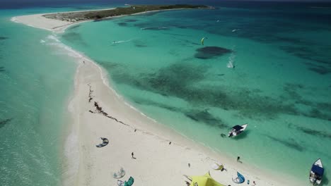 Kitesurfers-and-a-beach-camp-on-a-pristine-sandy-isthmus-with-turquoise-waters,-aerial-view